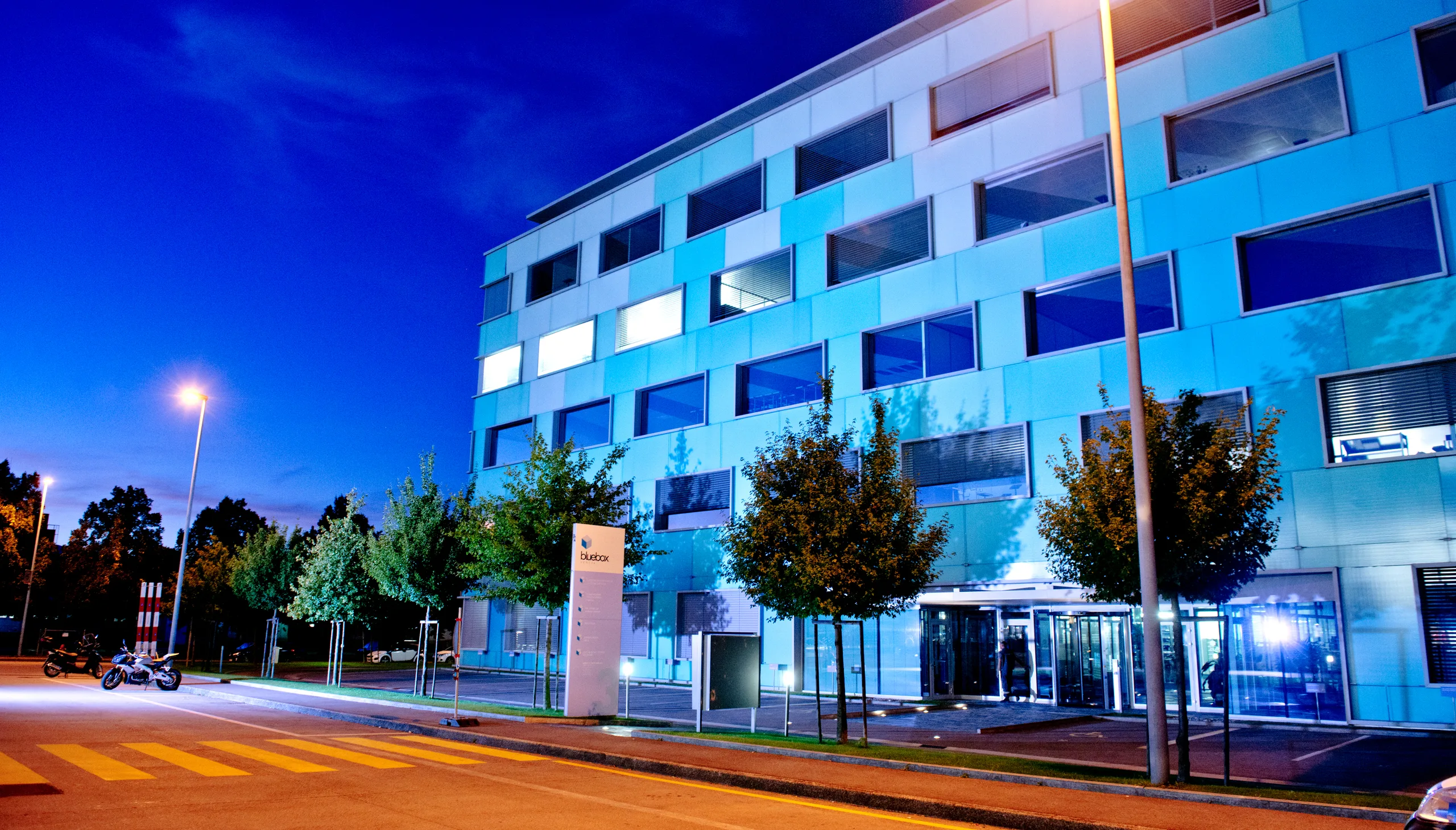 Bâtiment de bureaux moderne éclairé en soirée, en zone d'activités genevoise