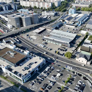 Vue aérienne d'un secteur d'activités genevois, avec commerces, parkings et axes routiers