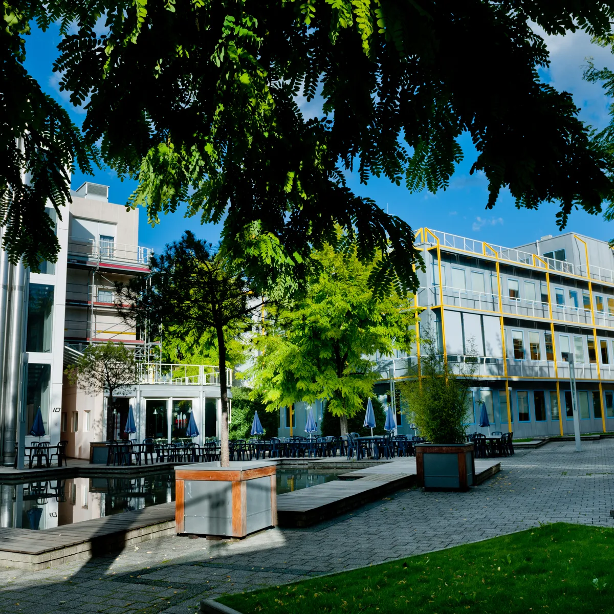 Cour paysagère d'un écoParc avec terrasse, bassin et arbres entre bâtiments d'activités