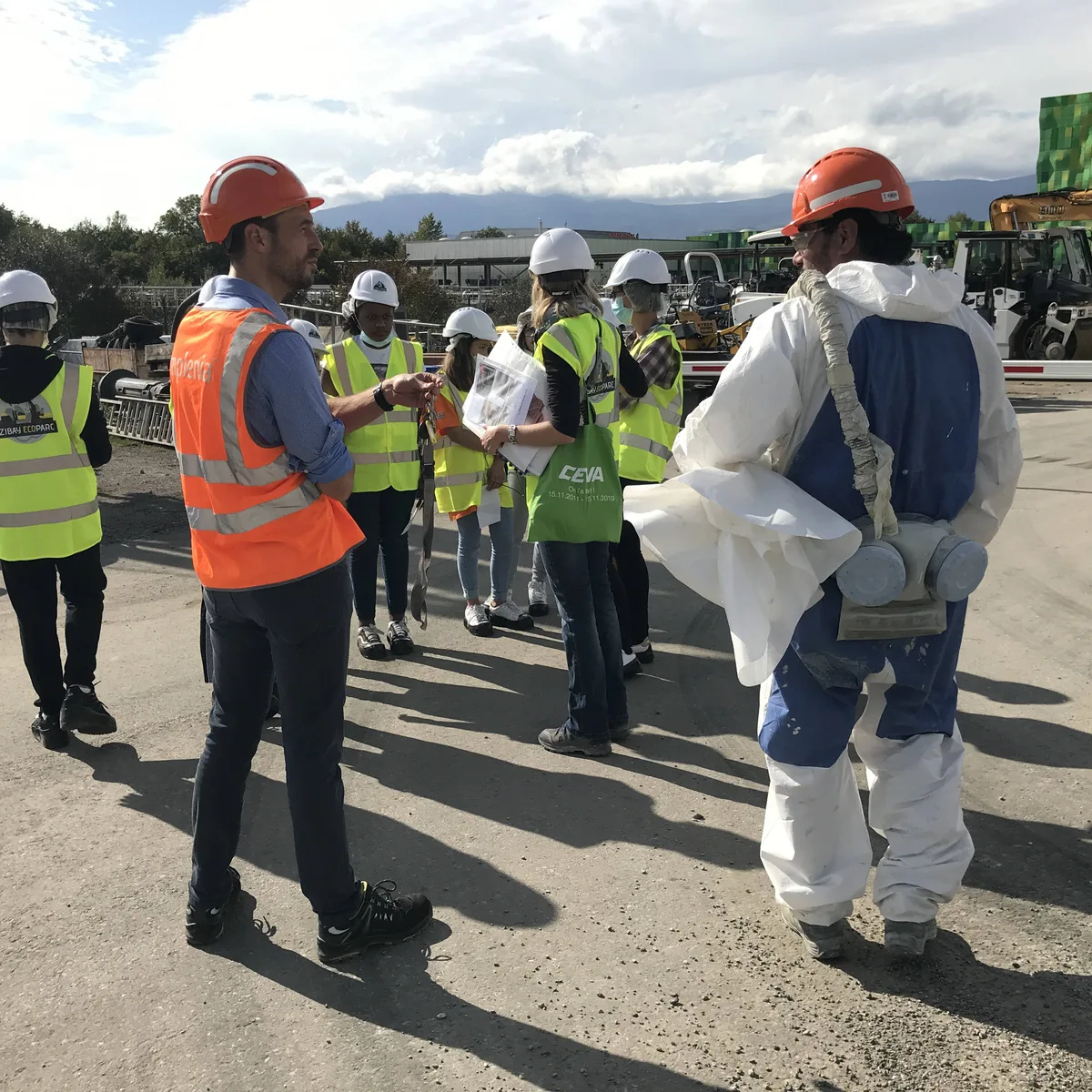 Visite de chantier : groupe en gilets et casques, un intervenant en combinaison de protection — zone ZIBAY