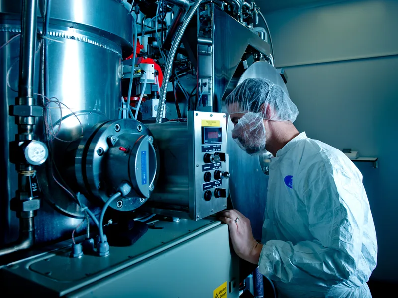 Technicien en tenue stérile pilotant une installation industrielle en salle blanche