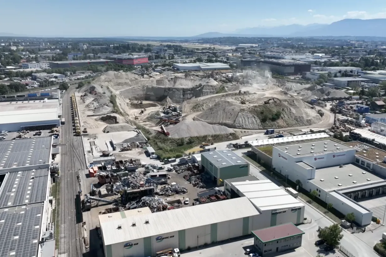 Vue aérienne d'une zone industrielle avec une vaste zone d'extraction, bordée de halles