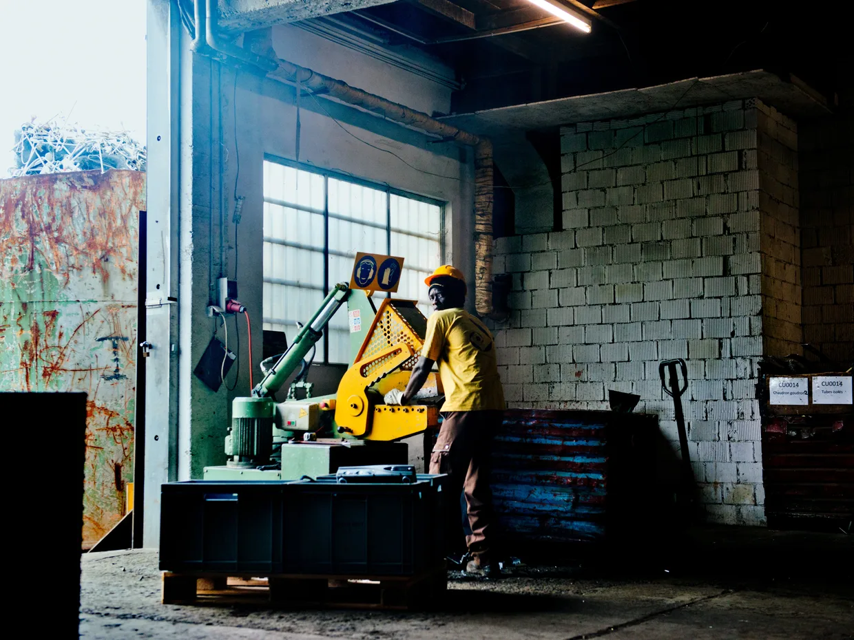 Ouvrier casqué en gilet jaune utilisant une machine-outil dans un atelier industriel